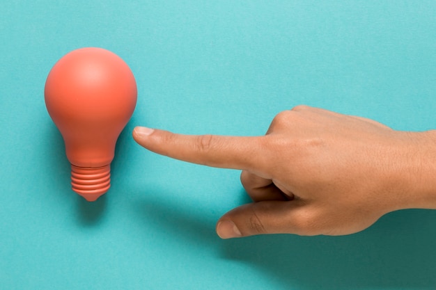 Free photo hand showing on pink lamp on colored surface