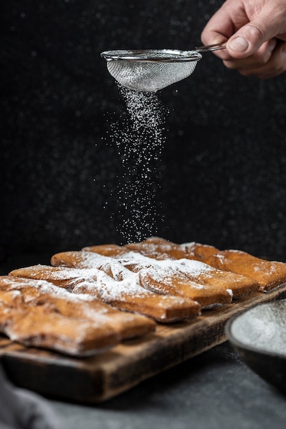 Free photo hand sieving powdered sugar on desserts