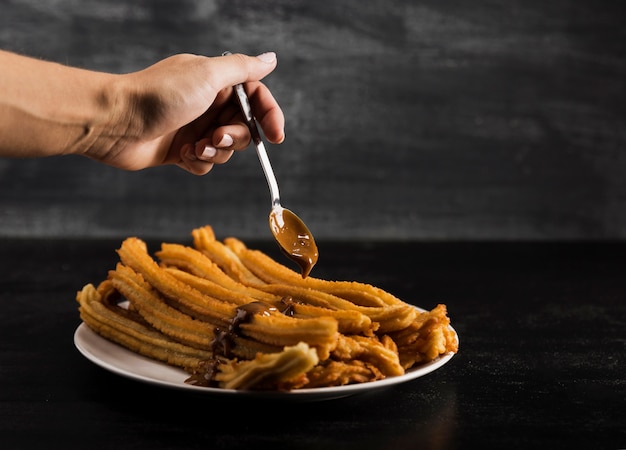 Free photo hand and spoon with delicious fried churros