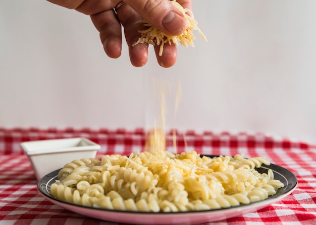 Hand sprinkling cheese on pasta