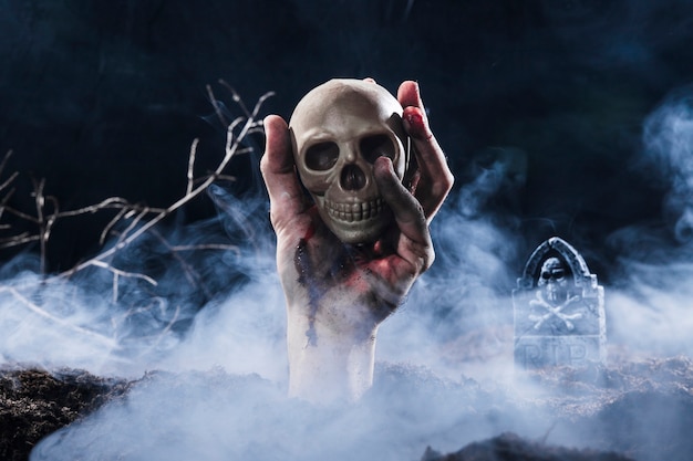 Free photo hand sticking out of ground and holding skull