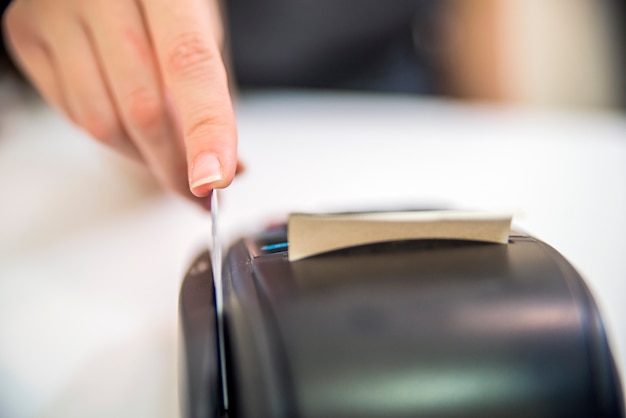 Free photo hand swipe red credit through payment terminal. debit card swiping on pos terminal. credit card reader machine on white background