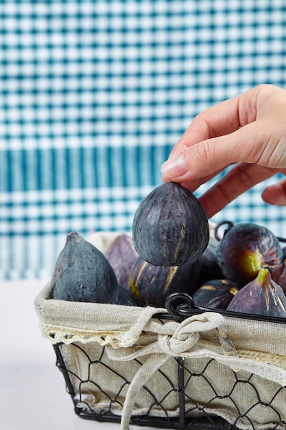 Free photo hand taking a fig from the basket.