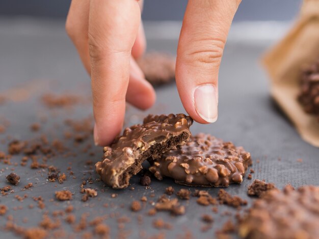 Hand taking nipped chocolate cookie from table