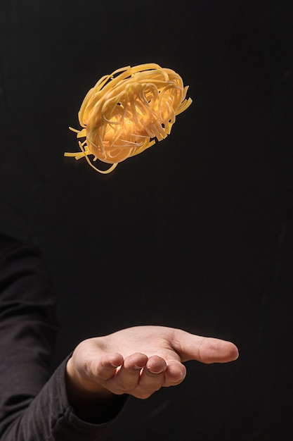 Free photo hand throwing pasta up in the air