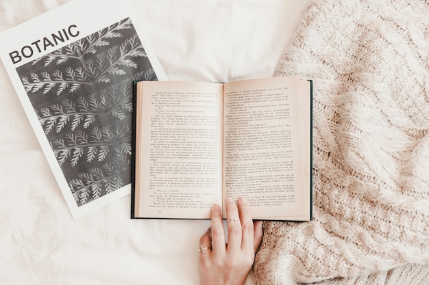 Hand touching book on poster and blanket on bedsheet