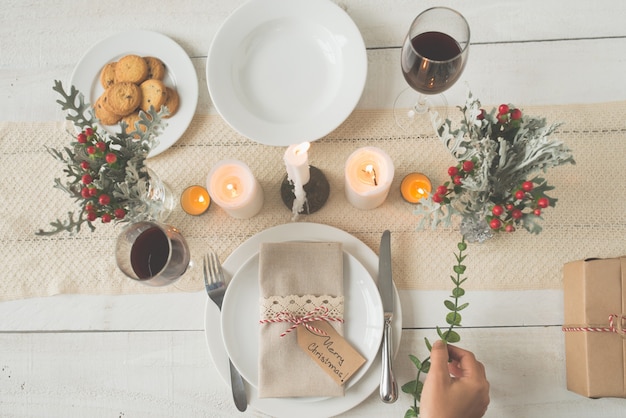 Free photo hand of unrecognizable woman putting green branch on christmas dinner table