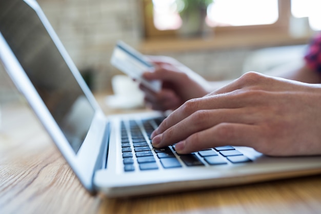 Hand using a laptop to make an online payment in coffee shop