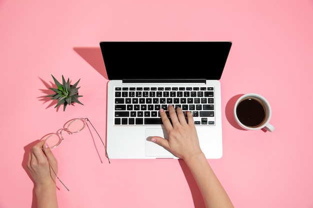 Hand using laptop on pink surface