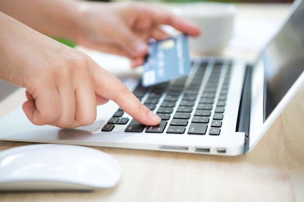 Hand with a credit card and a laptop