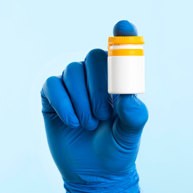 Hand with latex glove holding medicine bottle