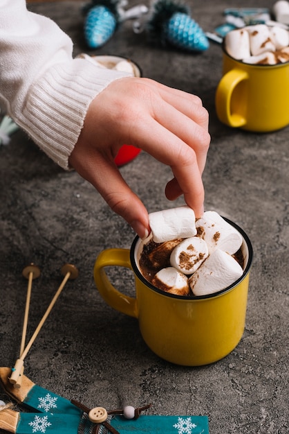 Free Photo hand with marshmallow near cup and christmas toys 