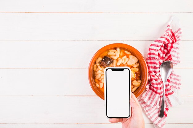 Hand with mobile on table with food plate