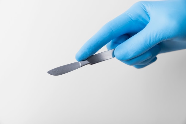 Free photo hand with rubber glove holding medical scalpel