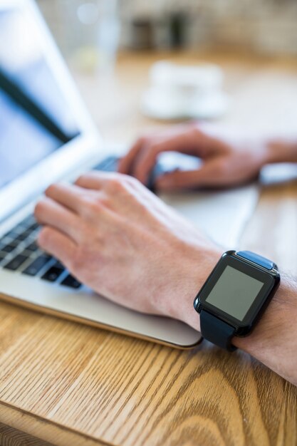 Hand with smartwatch using a laptop in coffee shop