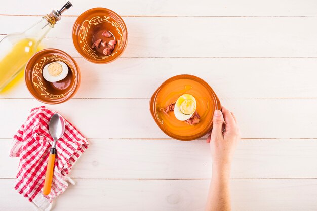 Hand with soup plate on cooking table