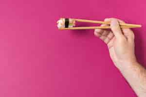 Free photo hand with sushi on chopsticks