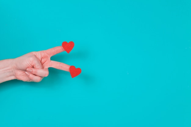 Free photo hand with two fingers with two hearts on a blue background