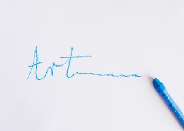 Free photo hand written art text near blue crayon on a white background