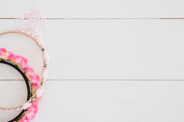 Free photo handmade rose hairband and beads on white wooden desk