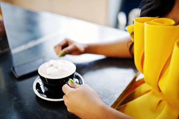 Free Photo hands of african american woman at yellow dreess with cup of cappuccino