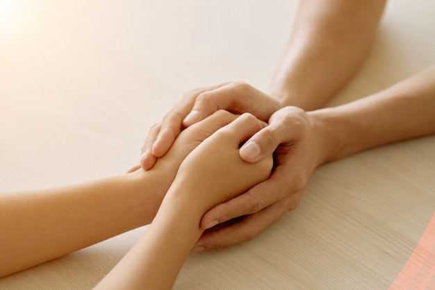 Hands of anonymous supportive friend holding hands of woman