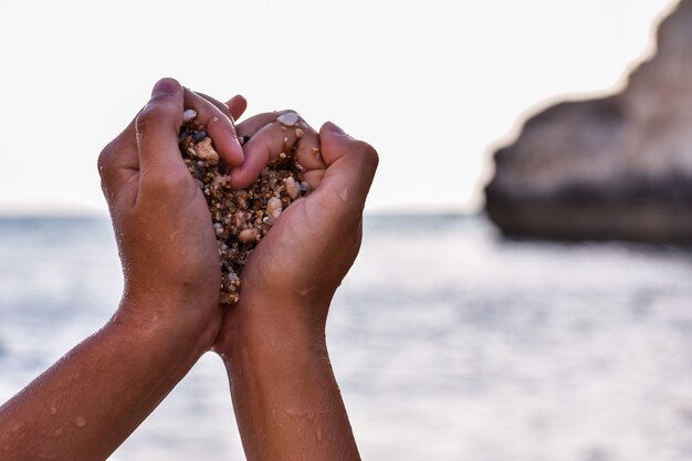 Hands of a black person grabbing stones in the shape of a heart