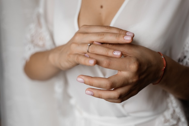 Hands of a bride with an engagement ring with diamond and a tender manicure