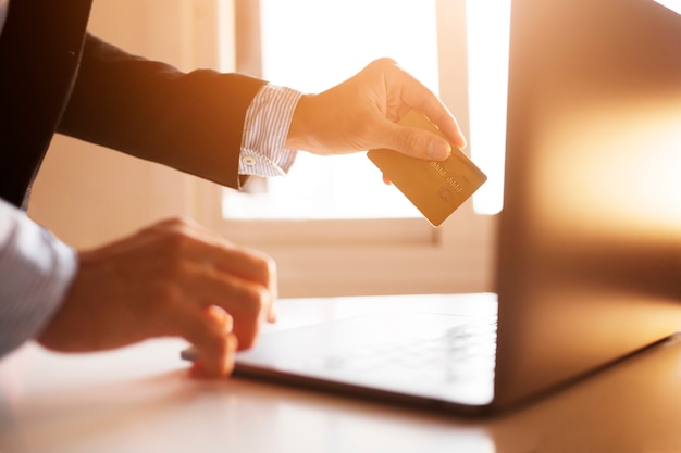 Hands of a businessman using laptop and card on the internet