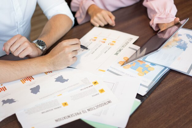 Hands of businesspeople discussing marketing reports and presentation on tablet