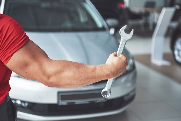 Free photo hands of car mechanic with wrench in garage.