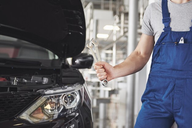 Hands of car mechanic with wrench in garage.