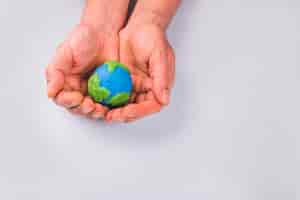 Free photo hands of child holding colorful clay model of planet earth