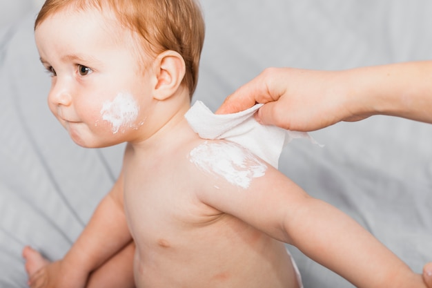 Hands cleaning baby with baby wipe