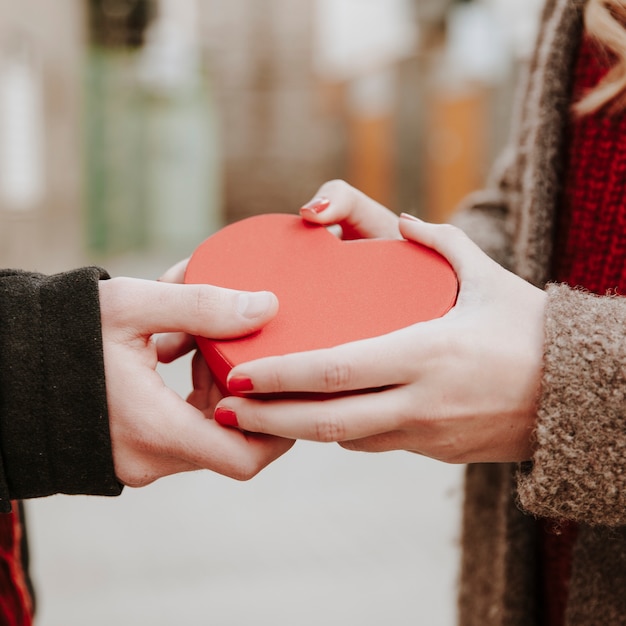 Free photo hands of couple with heart shaped box