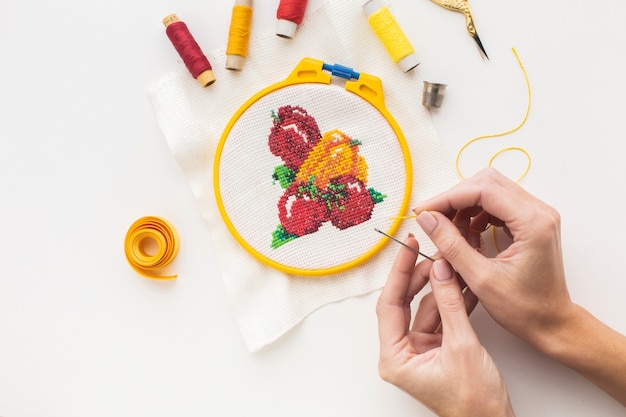 Hands creating a design with needle and sewing thread