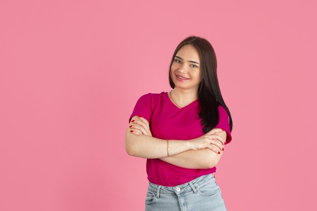 Hands crossed.Monochrome portrait of young caucasian brunette woman isolated on pink wall.