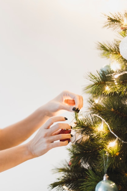 Hands decorating illuminated christmas tree