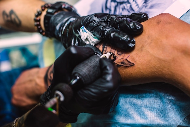 Free photo hands drawing tattoo on arm with needle machine