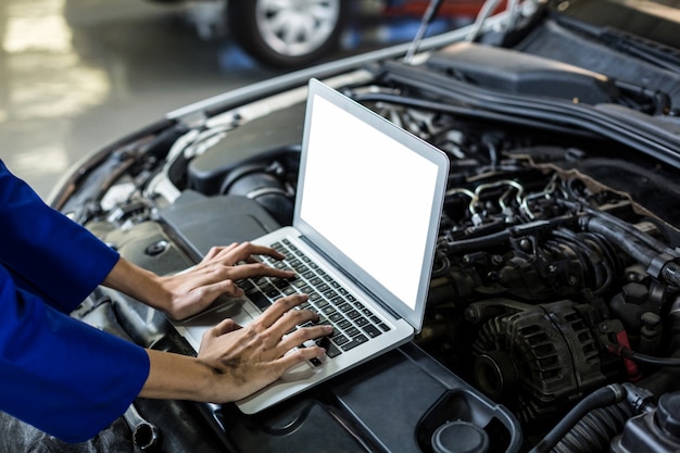 Hands of female mechanic using laptop