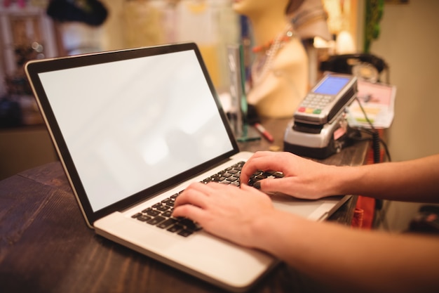 Hands of female staff using laptop at a counter