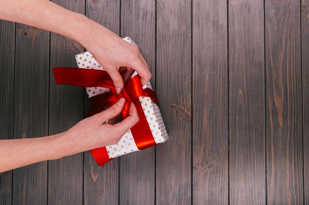 Free Photo hands fix red bow tie on white present box