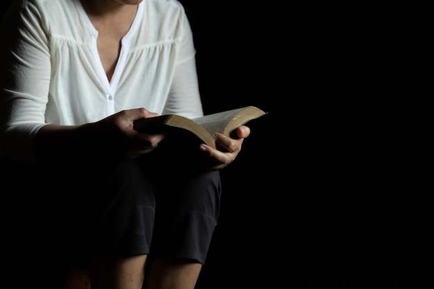 Hands folded in prayer holding a Holy Bible in church 