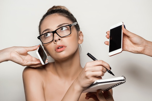 Hands giving phones to young beautiful businesswoman holding notebook