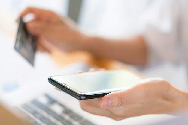 Hands holding a credit card using laptop computer and mobile phone for online shopping