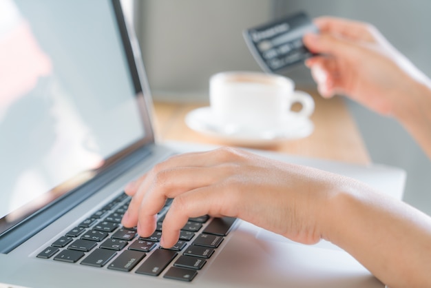 Hands holding a credit card and using laptop computer for online