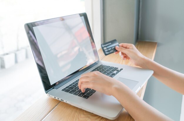 Hands holding a credit card and using laptop computer for online