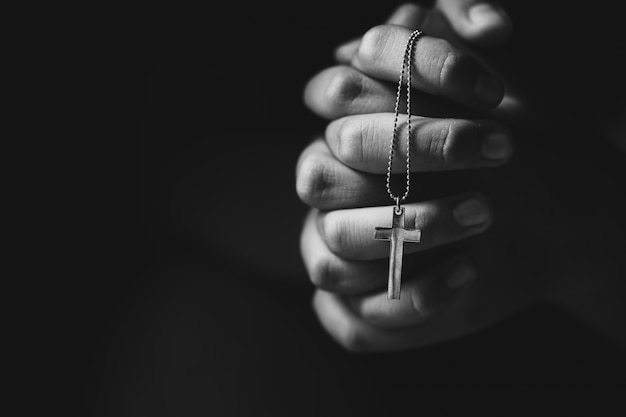 Hands holding cross while praying.