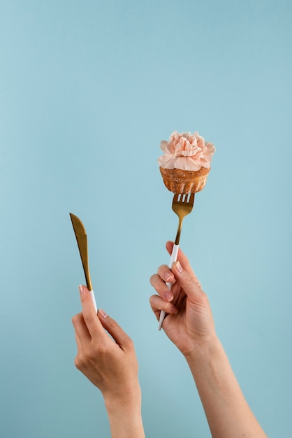 Hands holding cutlery with cupcake