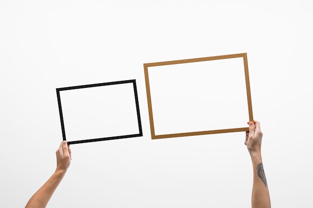 Free Photo hands holding dark and wooden frames